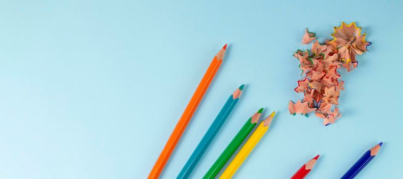 banner with Sharpened colored pencils and pencil shavings on pastel blue color. Rainbow or LGBT pencils. Top view