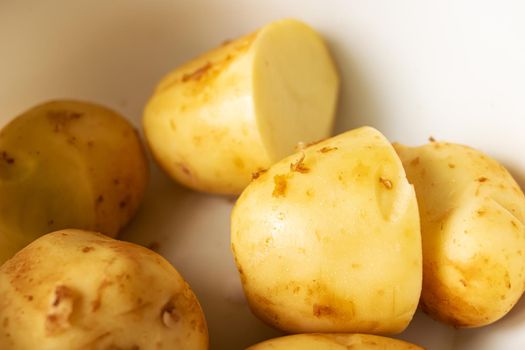 Yellow peeled potatoes in a bowl close up