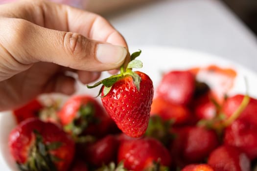 Heap of ripe red strawberries with green leaves close up