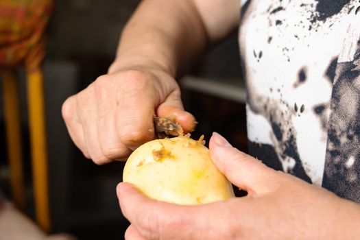 Hands peeling potatoes with a knife close up