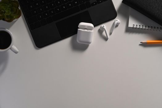 Modern workspace with laptop computer, wireless earphones, coffee cup and notebook.