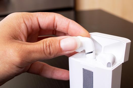 Hand takes out white wireless earbuds close up