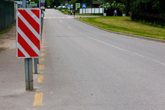 warning red and white diagonal striped vertical marking 8.22.2 sign at the end of road fence, separating road and