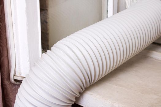 Corrugated pipe from the air conditioner on the windowsill close up