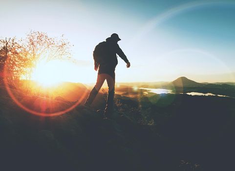 Man in rocks. Climbing hiking silhouette in fall mountains.  The climber in inspirational sunrise landscape on mountain peak. 