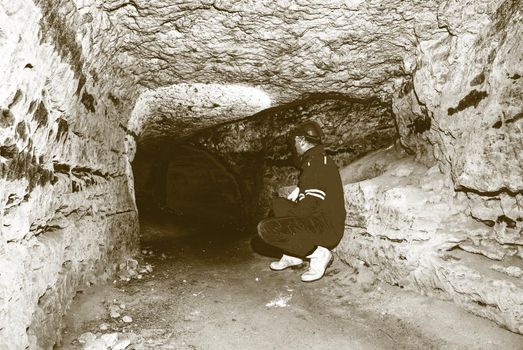 Miner man underground in a mine tunnel.  Worker in overalls, safety helmet and gummy boots is busy with work. Solarize effect