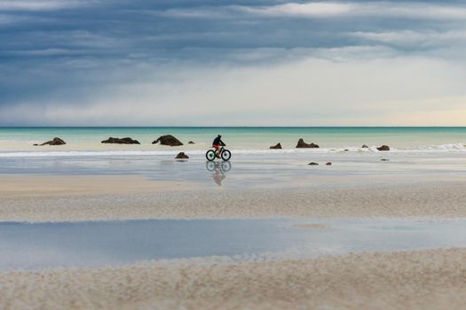 Cyclist rides a bike along the Atlantic Ocean at Normandy