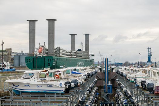 DIEPPE, FRANCE - DECEMBER 24, 2018: Maritime transport of wind turbine blades and motor boat parking at a port of Dieppe in Normandy