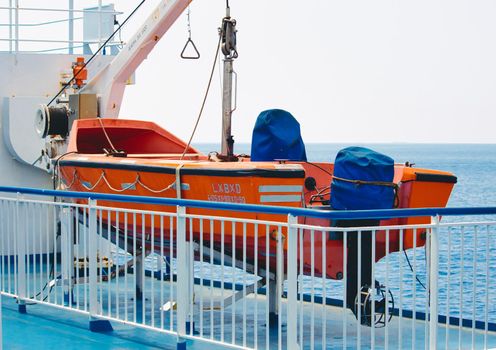 Orange lifeboat on deck of a sea vessel in the ocean