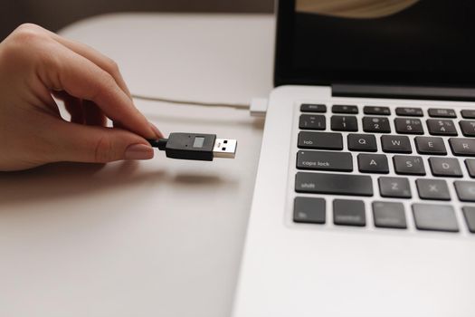 Female hand put USB adapter to copy file by laptop.