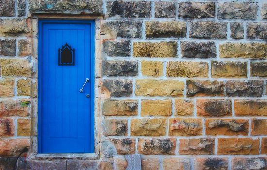 Blue door in a rough large stone wall facade
