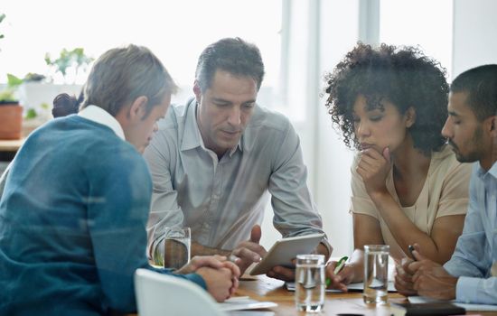 Shot of a group of professionals using wireless technology during a meeting.