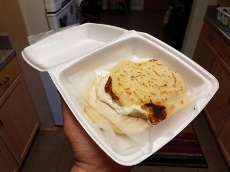 cheesy papusa Salvadorian food in held in foam container in kitchen