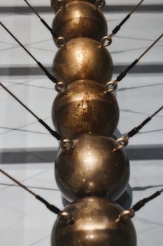 Close-up of a Newton's cradle made up of a row of large copper balls