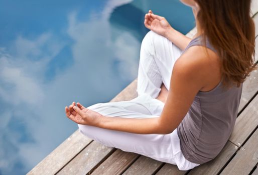 Cropped closeup of a young woman meditating poolside.