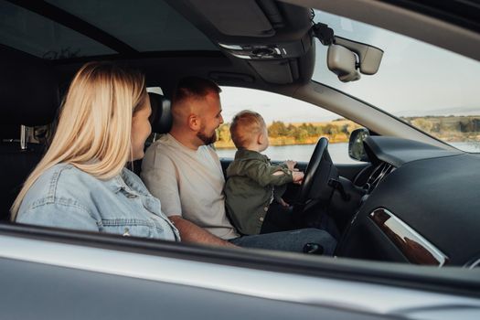 Young Family Enjoying Road Trip Together, Mother and Father with Their Son Sitting Inside Car