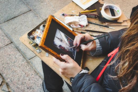 Female street artist painting a scene in Seville, Spain
