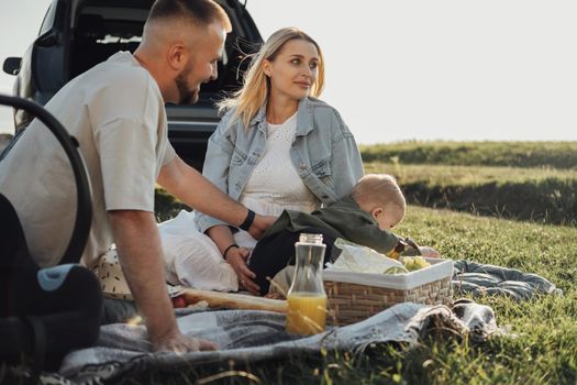 Young Family, Mom and Dad with Toddler Son Having Picnic Outdoors, Weekend Road Trip by the Car