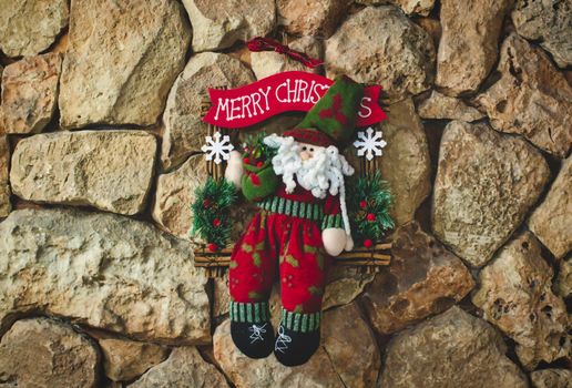 Santa clause Christmas decoration made with knitted wool hanging on a stone wall background