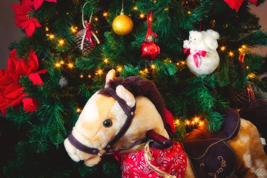 Christmas tree with bauble decorations and fairy lights with a toy rocking horse in front