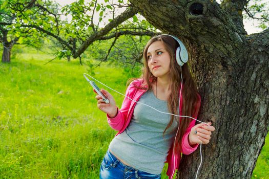 girl listening to music with headphones sitting in nature