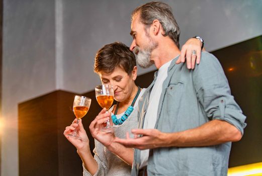 aged couple with glasses of wine in the kitchen