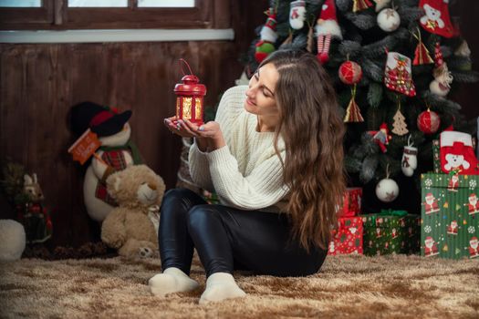 girl with a small flashlight in her hands on the background of a Christmas tree