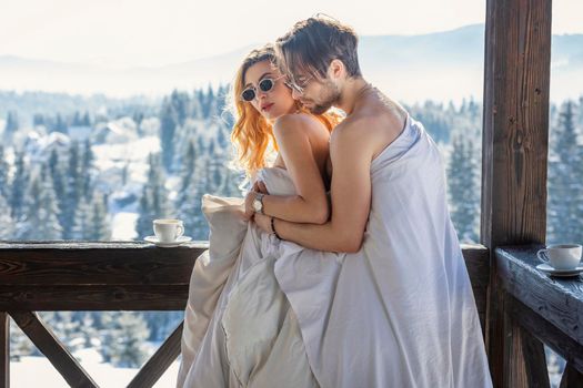 couple in winter in blankets on the background of mountains