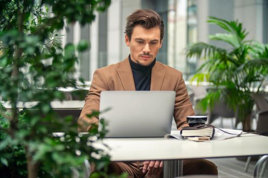 businessman sitting at a table in a cafe with a laptop