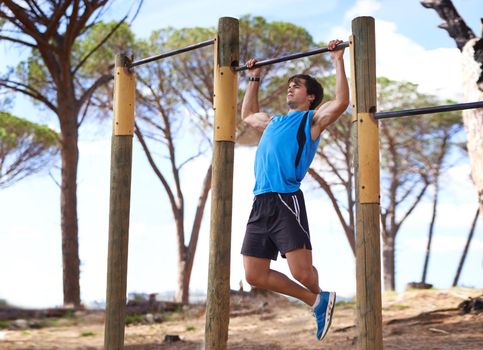 Young adult male using outdoor gym apparatus.