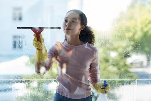 Shot of a young woman cleaning her window at home.
