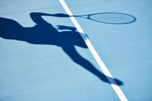 A shadow of a tennis player ready to serve.