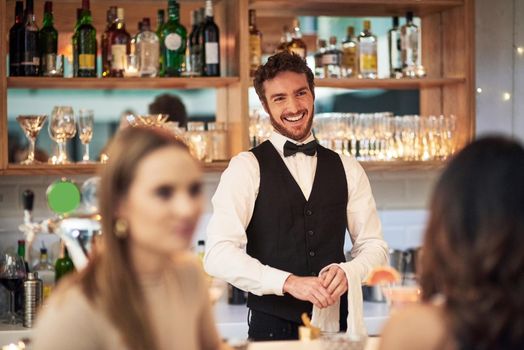 Cropped shot of a handsome young waiter smiling while standing in a bar.