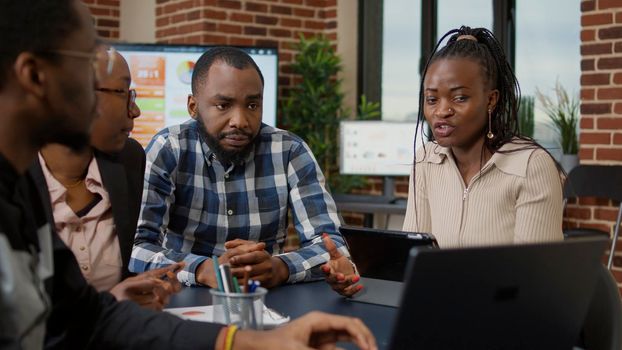 Team of african american people meeting in boardroom to do project briefing, brainstorming ideas and finding solution for business growth. People doing teamwork and collaborating on presentation.