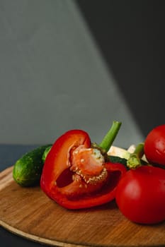 branches of fresh green asparagus, peppers, tomatoes and cucumbers on a wooden board, dark gray background, top view. Basic trend concept with copy space