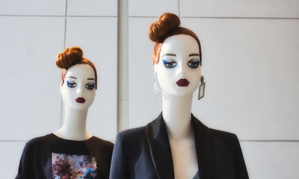 Two identical white fashion mannequins displaying modern clothes