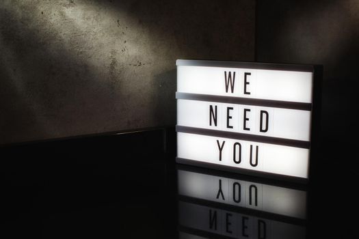 We need you recruitment message on a light box in a cinematic moody background
