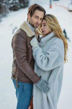 beautiful couple hugging in winter on the background of a snowy mountain