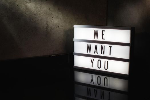 We want you recruitment message on a light box in a cinematic moody background
