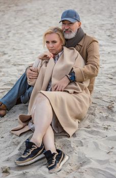 aged couple sitting on the beach near the sea