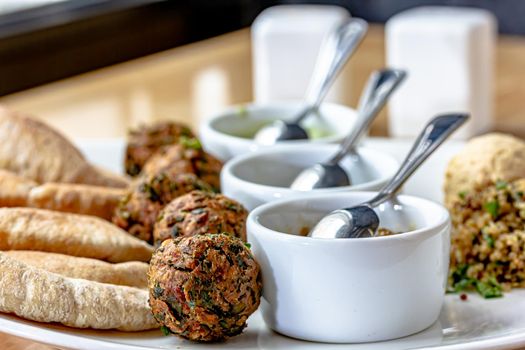 Traditional middle eastern homemade dishes falafel, pita, hummus and chickpea served with vegetables and spices on woodwn table. Top view