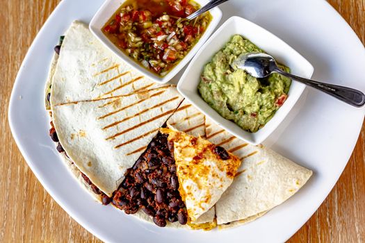 Savory crepe filled with spicy ground beef, cheese, kidney beans, lettuce and tomatoes. Topped with sour cream and served on a plate. Tex mex food.