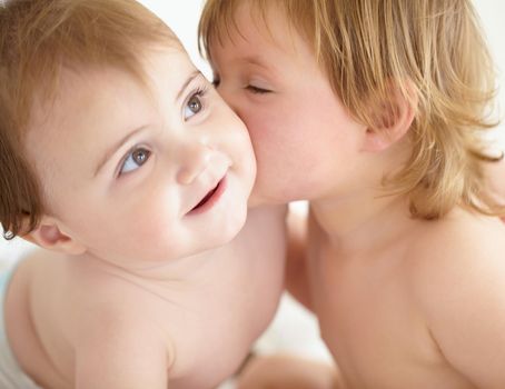 Closeup of a sweet little girl giving her baby sister a kiss on the cheek.