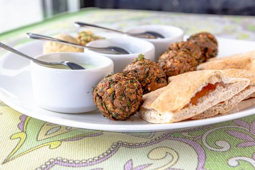 Traditional middle eastern homemade dishes falafel, pita, hummus and chickpea served with vegetables and spices on woodwn table. Top view