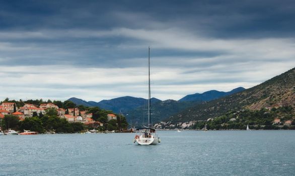 A yacht sailing off into the distance between the hills and mountains
