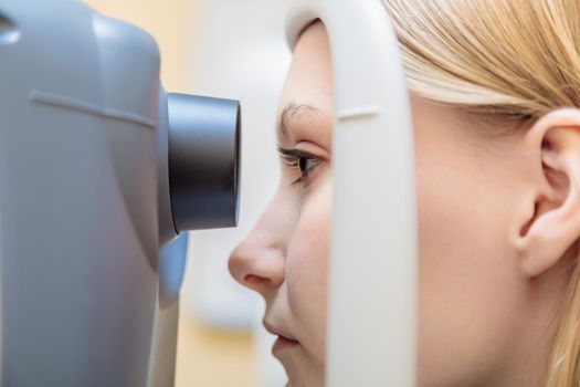 A young girl at the reception at the ophthalmologist checks her eyesight on a special apparatus. Close-up.