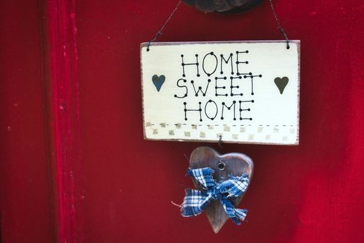 A cute Home Sweet Home sign hanging on a bright red door