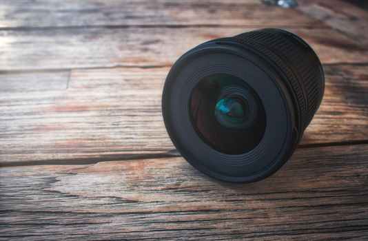 Camera lens on a rustic wooden table with soft light