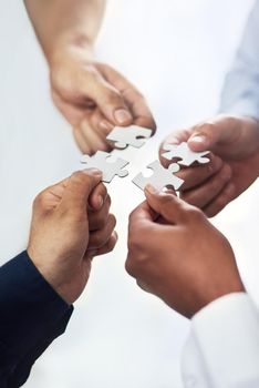 High angle shot of a group of unidentifiable businesspeople holding puzzle pieces together.