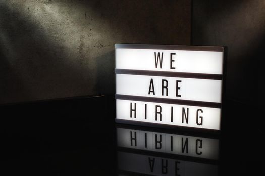 We are hiring recruitment message on a light box in a cinematic moody background